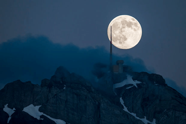 Supermoon Rising Above a Swiss Peak
